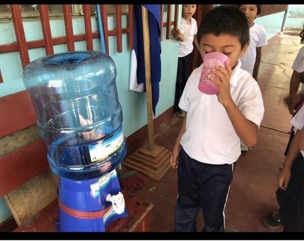 A child drinking water from a water jug