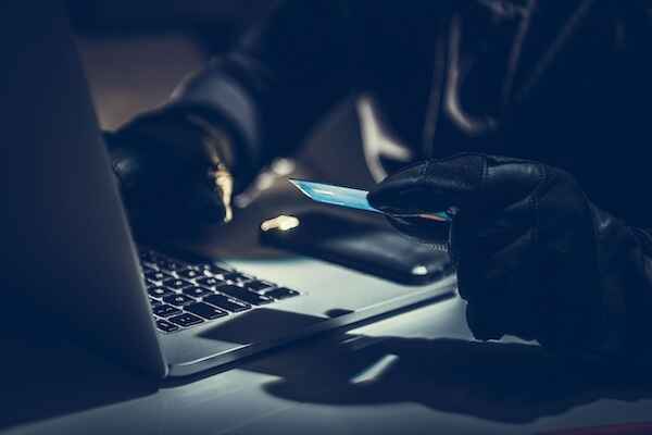 Person wearing black gloves with a laptop and holding a CC